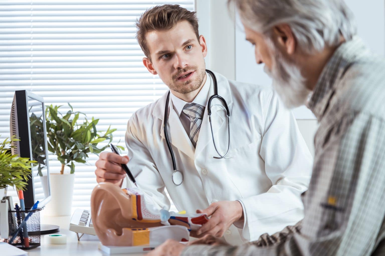 Audiologist speaking to a senior male patient about hearing loss.