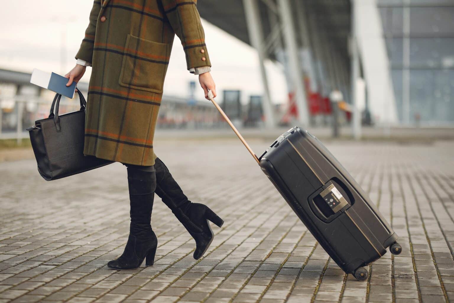 Woman with a suitcase walking into the airport.