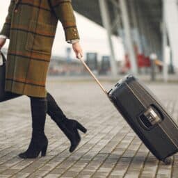 Woman with a suitcase walking into the airport.