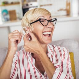 Woman putting in hearing aid looking happy