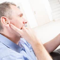 Man with hearing loss looks at phone at work