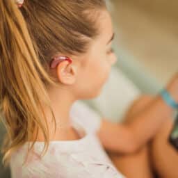Young girl wearing a hearing aid holding a tablet