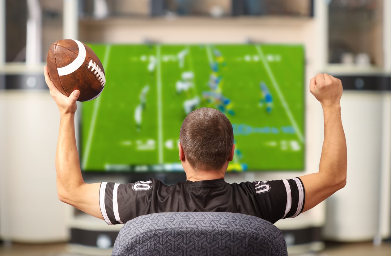 Man with football watches tv