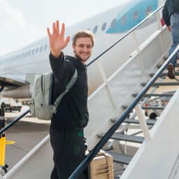 Happy man waving as he walks onto a plane