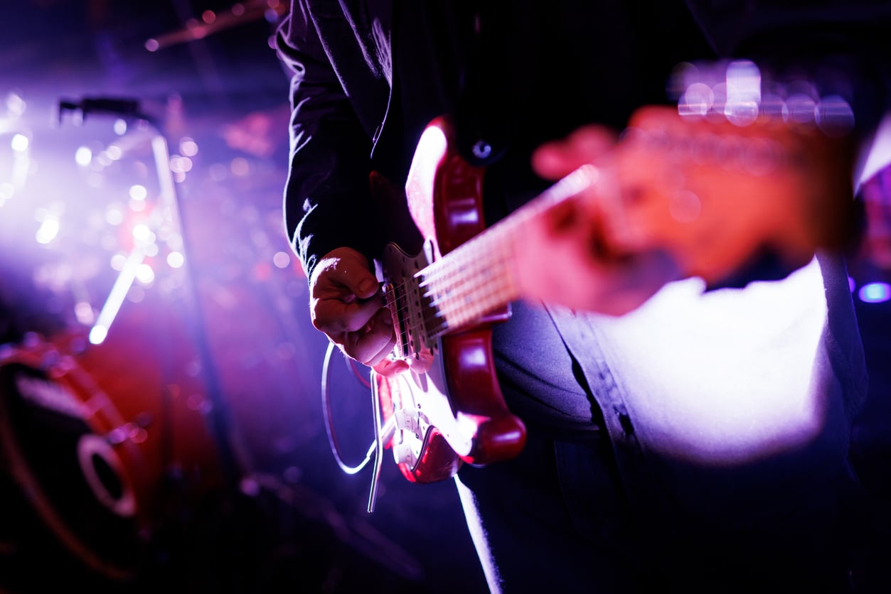 Close-up of a man playing a guitar at a concert.