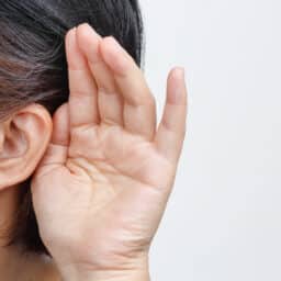 Woman holds hand behind ear