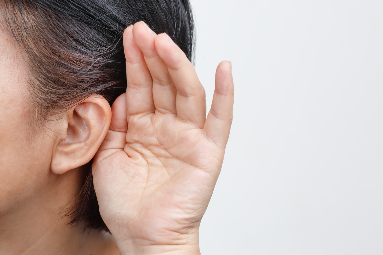 Woman holds hand behind ear